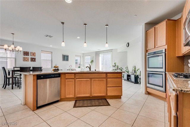 kitchen featuring light stone countertops, visible vents, a sink, decorative backsplash, and stainless steel appliances