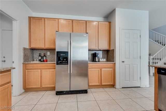 kitchen featuring light brown cabinets, light stone counters, decorative backsplash, light tile patterned floors, and stainless steel appliances