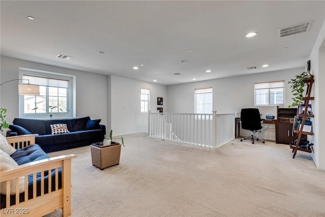 living area with plenty of natural light, visible vents, and light carpet