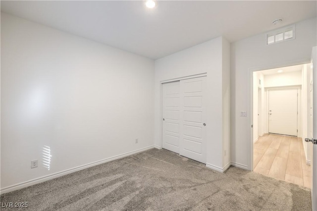 unfurnished bedroom with light carpet and a closet