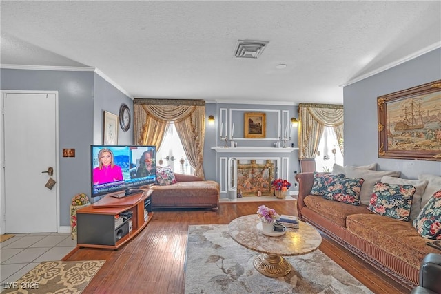 living room with ornamental molding, visible vents, and a textured ceiling