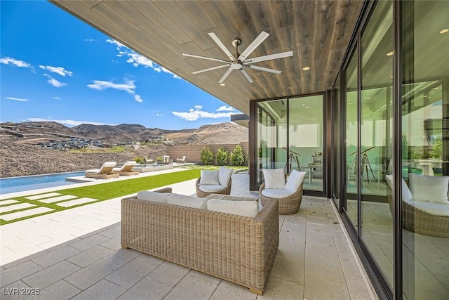 view of patio with an outdoor living space, a mountain view, and ceiling fan