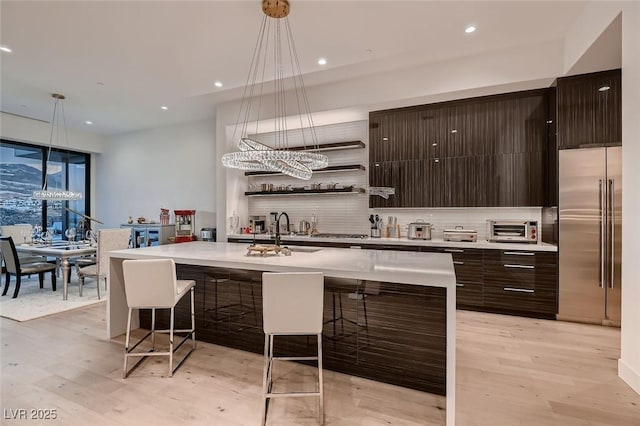 kitchen with a sink, modern cabinets, light countertops, and built in fridge