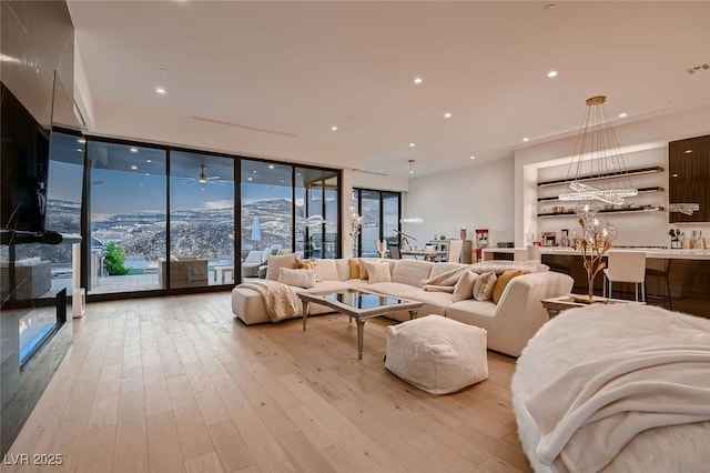 living area featuring recessed lighting, expansive windows, light wood-style floors, and visible vents