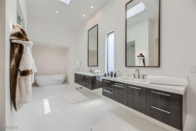 full bath featuring a sink, a freestanding tub, two vanities, and tile patterned floors