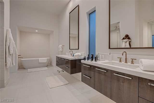 full bathroom with tile patterned floors, a freestanding bath, two vanities, and a sink