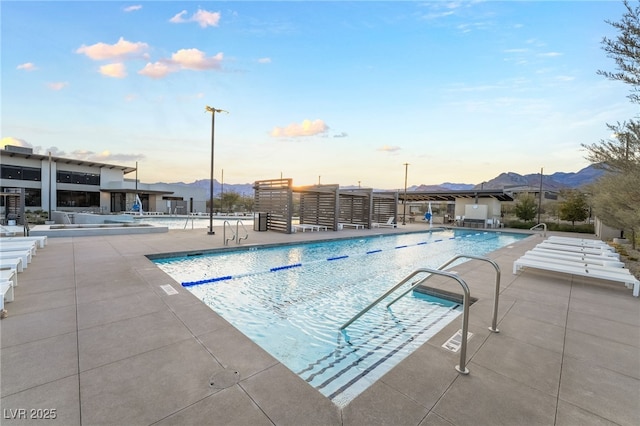 pool at dusk with a mountain view and a patio area