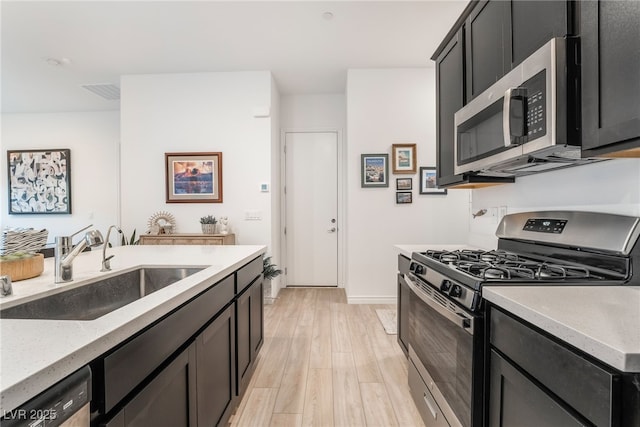 kitchen with sink, appliances with stainless steel finishes, and light wood-type flooring