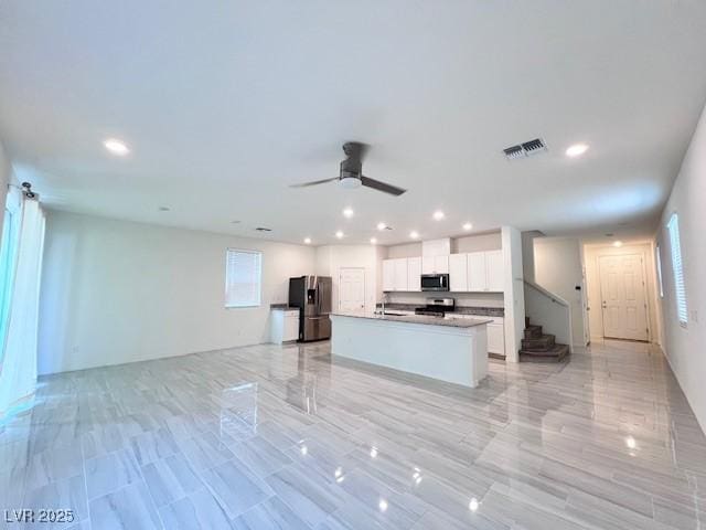 kitchen featuring a center island with sink, white cabinetry, ceiling fan, and appliances with stainless steel finishes