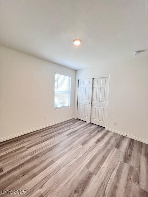 unfurnished bedroom with light wood-type flooring and a closet