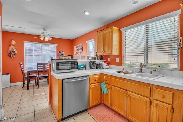 kitchen featuring stainless steel appliances, tile counters, light tile patterned flooring, sink, and kitchen peninsula