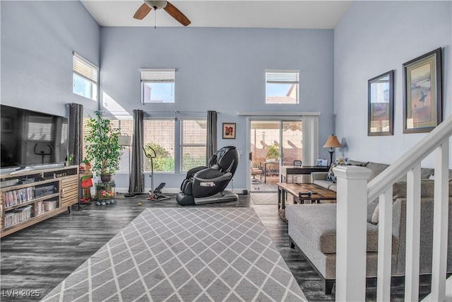 living room with a towering ceiling, dark hardwood / wood-style floors, and a healthy amount of sunlight