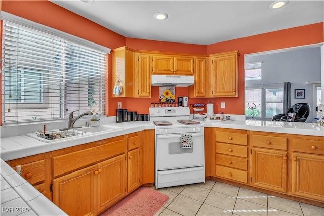 kitchen with white range with electric stovetop, light tile patterned floors, tile counters, and sink