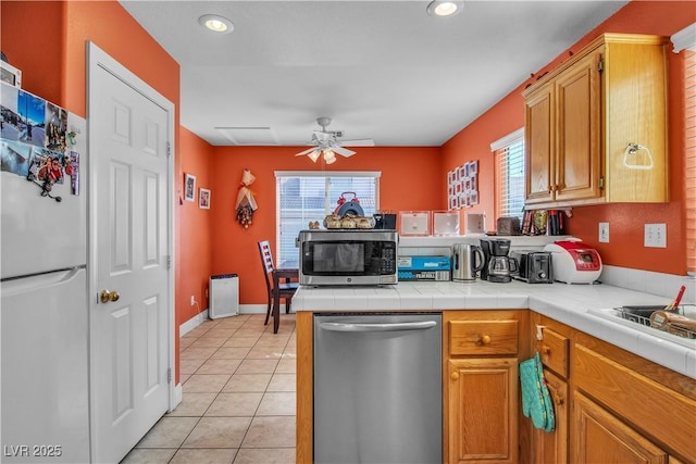 kitchen featuring a wealth of natural light, stainless steel appliances, light tile patterned floors, and tile counters