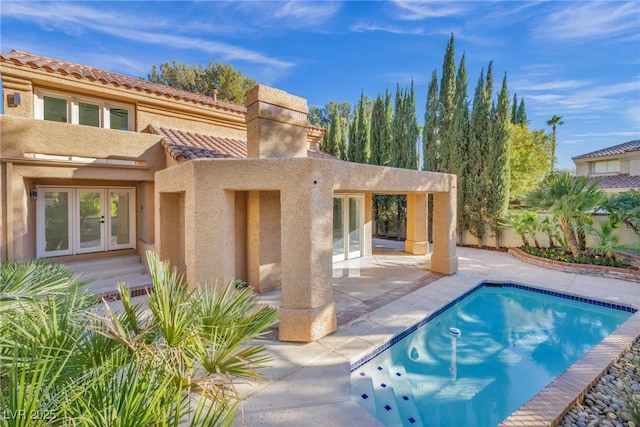 back of property featuring stucco siding, an outdoor pool, a patio, and french doors