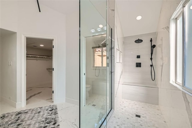 bathroom featuring baseboards, toilet, marble finish floor, a walk in closet, and a walk in shower