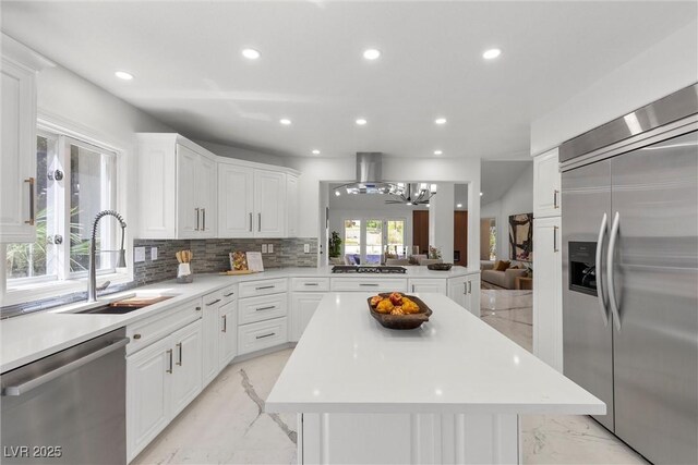 4961 Tierra Del Sol Dr, Las Vegas, NV 89113 - kitchen featuring appliances with stainless steel finishes, light marble finish flooring, recessed lighting, a center island, and decorative backsplash