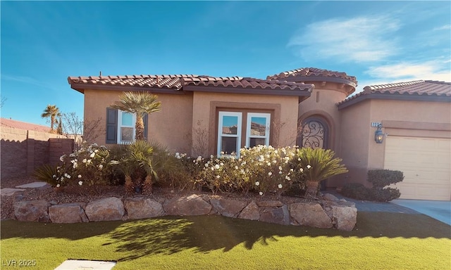 mediterranean / spanish-style house with a garage, stucco siding, a tile roof, fence, and a front yard