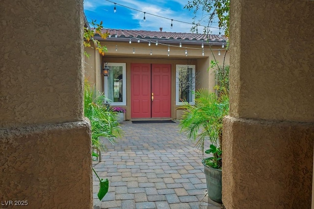 entrance to property featuring a tile roof and stucco siding