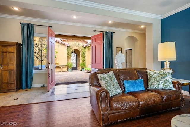 living room featuring baseboards, arched walkways, ornamental molding, wood finished floors, and recessed lighting