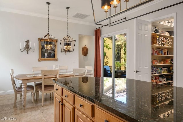 kitchen featuring dark stone counters, hanging light fixtures, visible vents, and crown molding