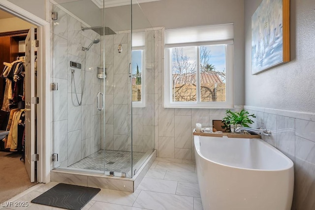 bathroom with a stall shower, a spacious closet, tile walls, and a soaking tub