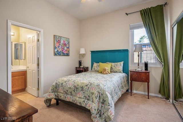 bedroom with light carpet, ensuite bath, and baseboards