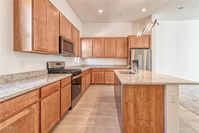 kitchen featuring a kitchen island with sink, stainless steel appliances, light stone countertops, sink, and light tile patterned floors