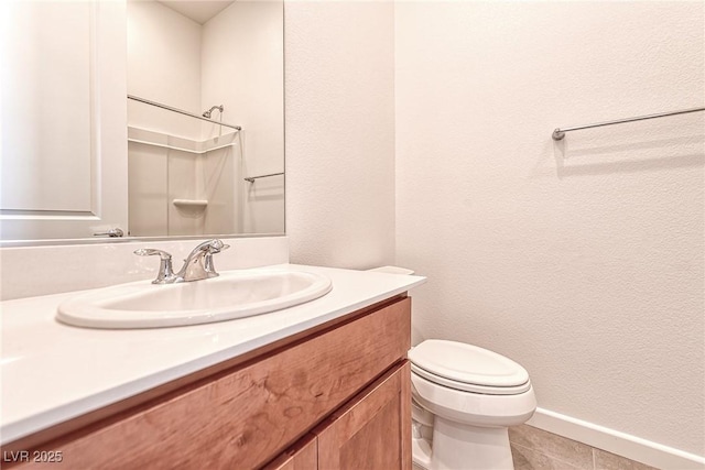 bathroom featuring toilet, vanity, and a shower