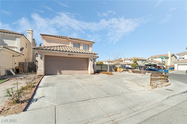 mediterranean / spanish home with driveway, a tile roof, an attached garage, fence, and stucco siding