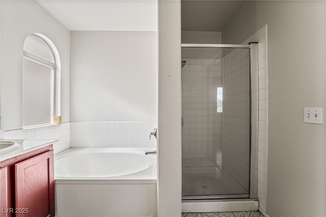 bathroom with a stall shower, a garden tub, and vanity