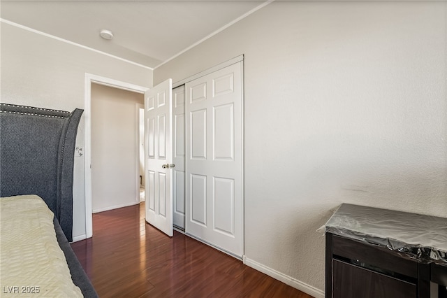 bedroom with a closet, dark wood-style flooring, and baseboards