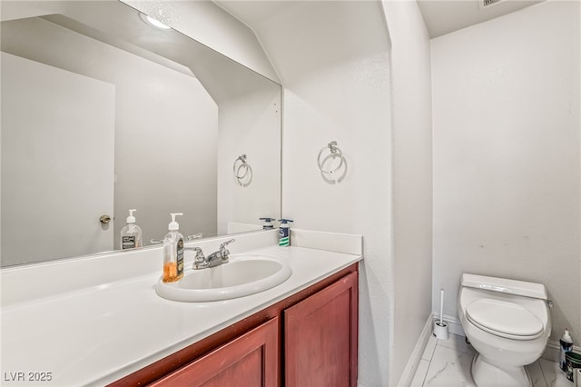 half bathroom with marble finish floor, baseboards, vanity, and toilet