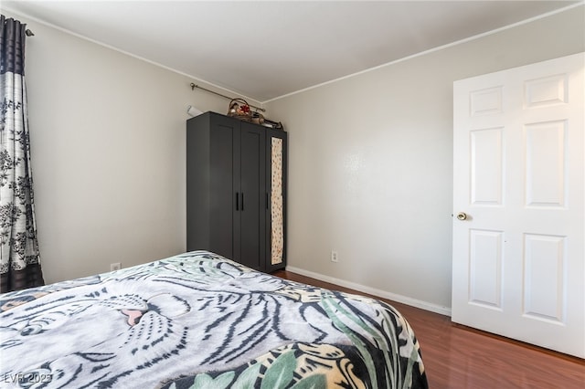 bedroom with baseboards, dark wood-type flooring, and ornamental molding