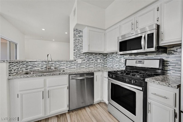 9050 W Warm Springs Rd Unit 2153, Las Vegas, NV 89148 - kitchen featuring appliances with stainless steel finishes, a sink, white cabinets, tasteful backsplash, and light stone countertops