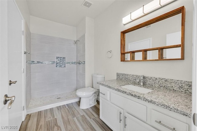 bathroom featuring toilet, vanity, and tiled shower