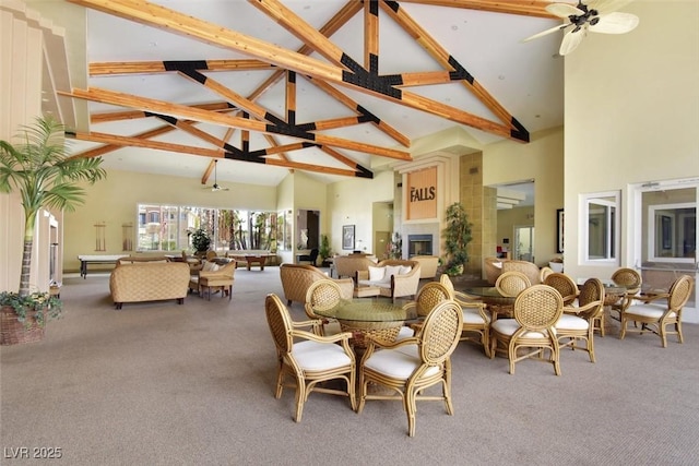 carpeted dining area with a fireplace, high vaulted ceiling, and beamed ceiling