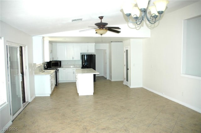 kitchen featuring black refrigerator, vaulted ceiling, a center island, sink, and white cabinetry