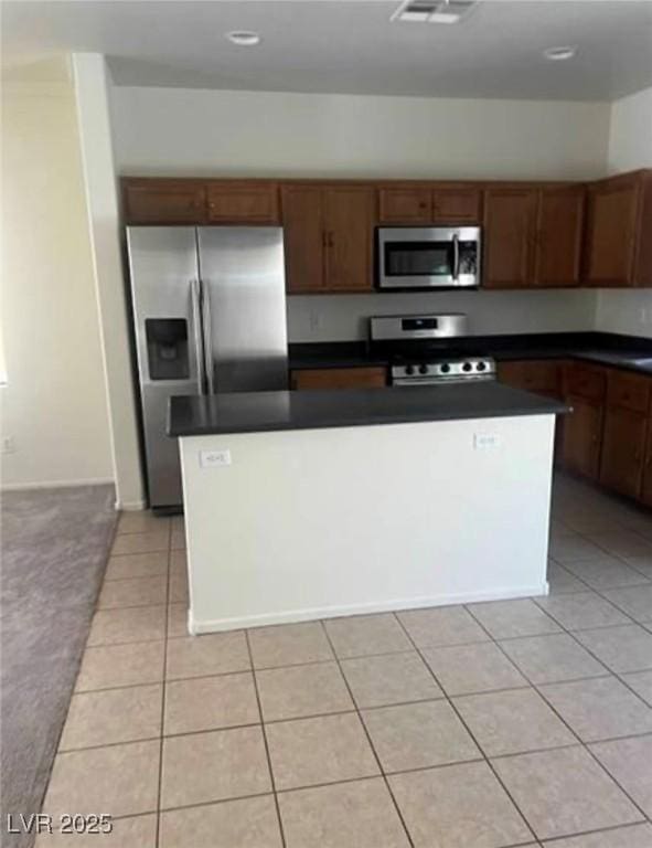 kitchen with appliances with stainless steel finishes, light tile patterned floors, and a kitchen island