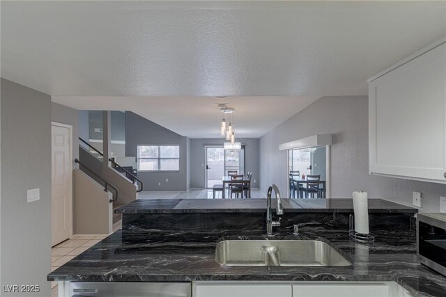 6250 W Flamingo Rd Unit 7, Las Vegas, NV 89103 - kitchen with a textured ceiling, light tile patterned floors, sink, white cabinetry, and dark stone countertops