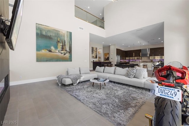 living area featuring a towering ceiling, baseboards, visible vents, and tile patterned flooring