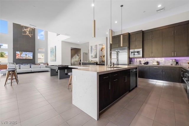 kitchen featuring stainless steel appliances, visible vents, decorative backsplash, a sink, and tile patterned floors