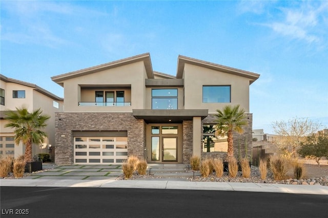 contemporary house featuring a garage, stone siding, driveway, and stucco siding