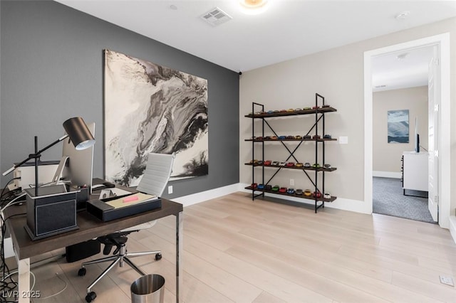 office area with visible vents, baseboards, and wood finished floors