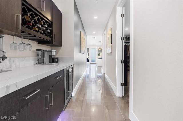 hallway featuring recessed lighting, beverage cooler, baseboards, and light tile patterned floors