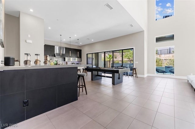 interior space with light countertops, light tile patterned flooring, wall chimney range hood, modern cabinets, and dark cabinets