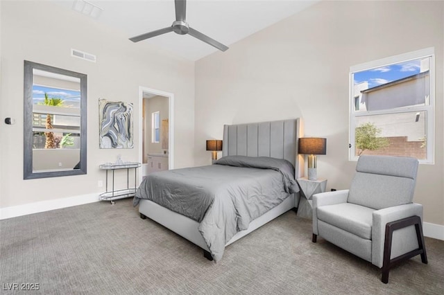 bedroom with ceiling fan, carpet floors, visible vents, baseboards, and ensuite bath