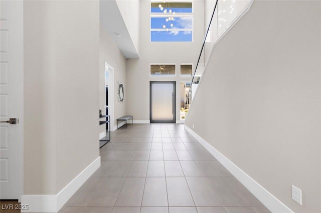 entryway with tile patterned flooring, a towering ceiling, and baseboards