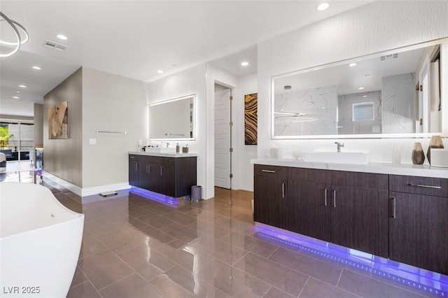 full bath with a freestanding tub, recessed lighting, two vanities, a sink, and visible vents