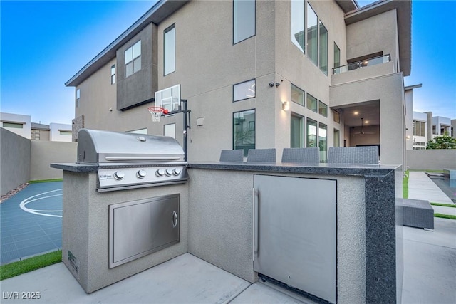 view of patio featuring a grill, fence, and exterior kitchen